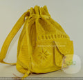 A handmade mustard yellow leather purse with intricate embossed patterns and tassel detailing.