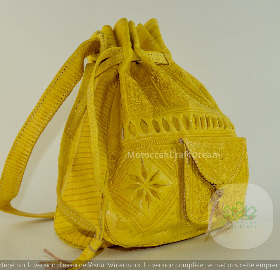 A handmade mustard yellow leather purse with intricate embossed patterns and tassel detailing.