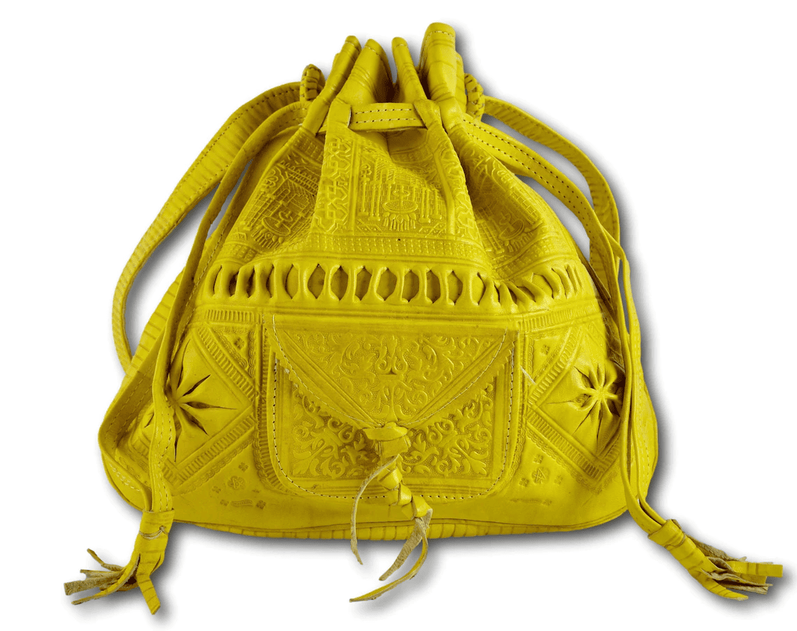 A handmade mustard yellow leather purse with intricate embossed patterns and tassel detailing.